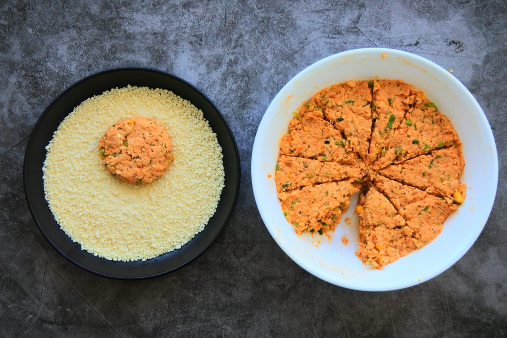 An overhead image showing the mixture for salmon croquettes/patties/cakes being divided and shaped into patties and covered in (gluten-free) panko breadcrumbs.