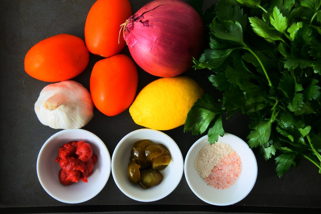 An overhead image of fresh ingredients needed for tomato salsa on a tray