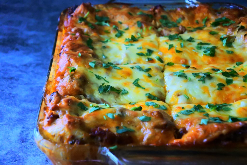An angled image of a dish of Kitrusy's Gluten free Lasagna after being baked, cooled, cut and topped with fresh parsley
