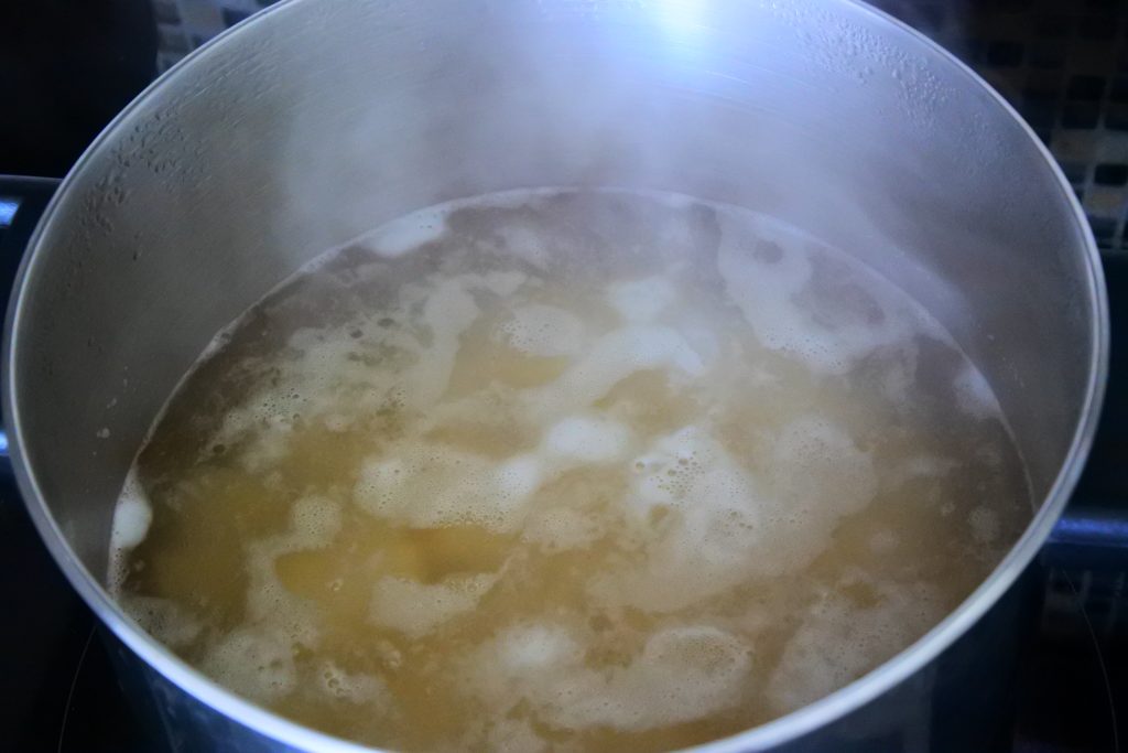 An angled image showing potato chunks being boiled in a pot