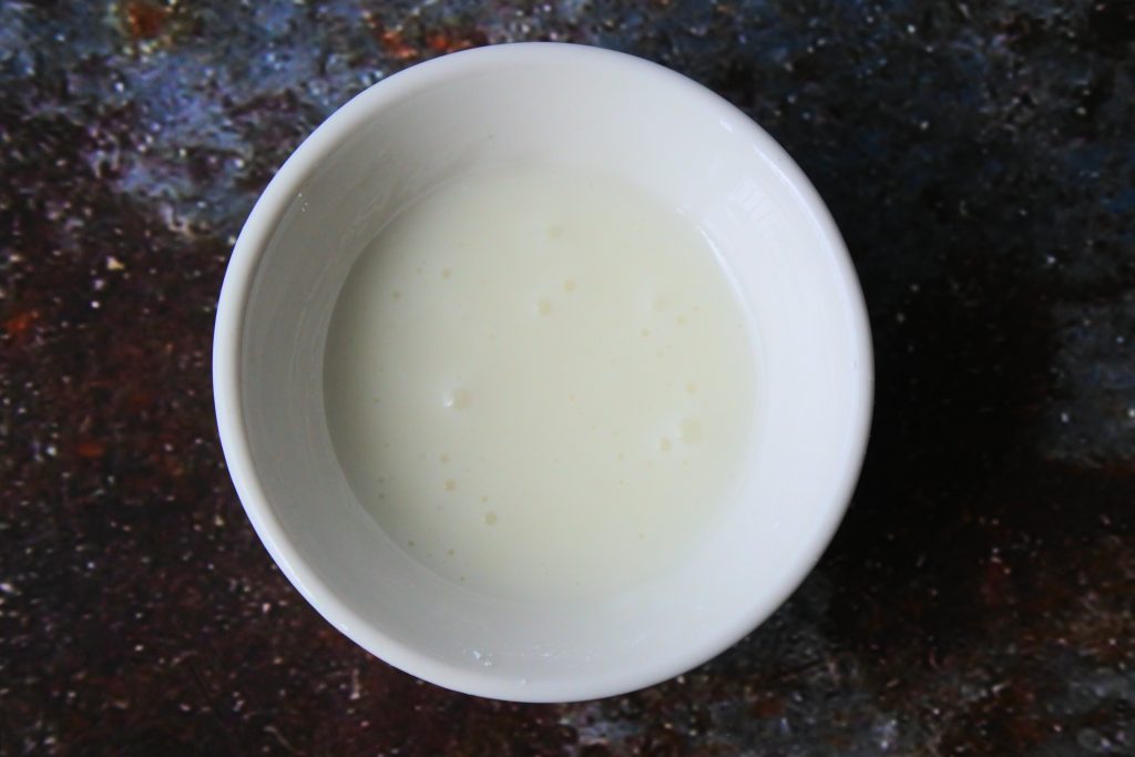 An overhead image showing milk mixed with icing sugar to make a thick frosting