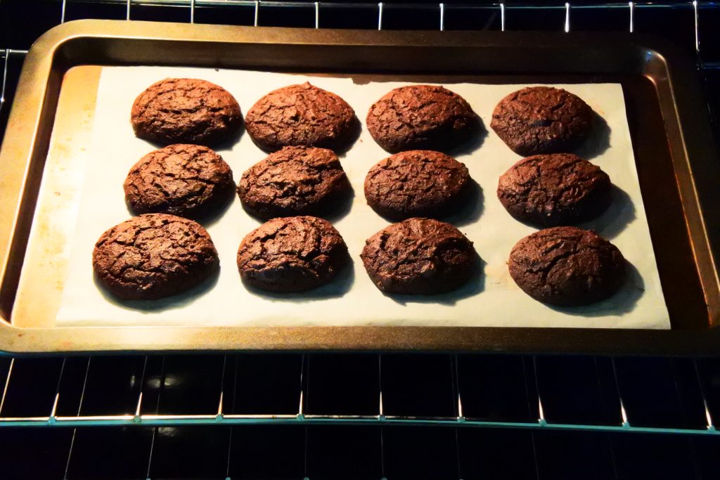 An angled image of a tray of freshly baked chocolate cake rounds for whoopie pies in the oven.