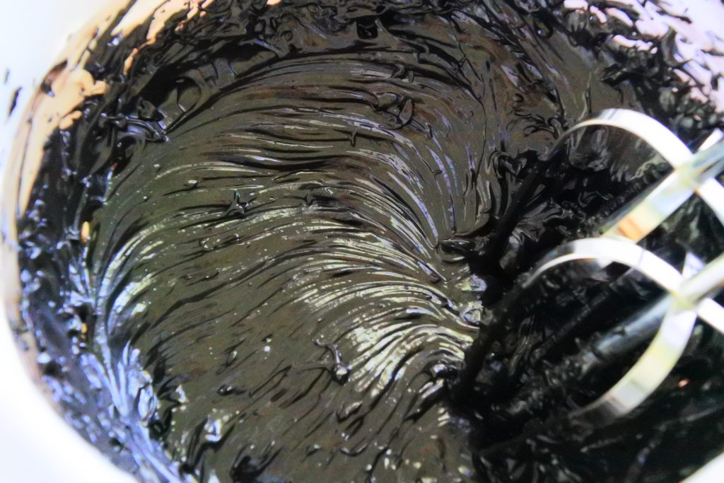A close up image showing a glossy black cocoa frosting after being whipped