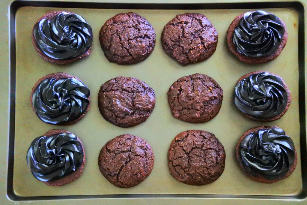 An over head image of chocolate whoopie pies with a black cocoa filling on a tray before being covered
