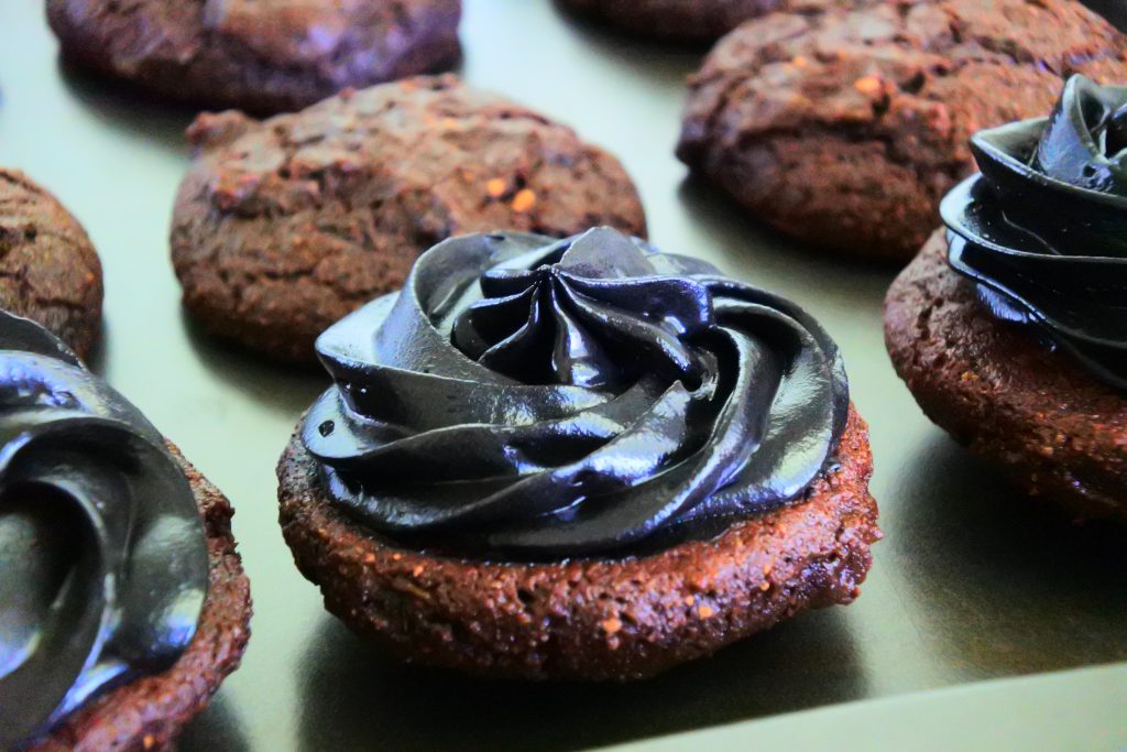 A head on image of chocolate whoopie pies with a black cocoa filling on a tray before being covered