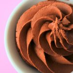 An angled image showing a piped swirl of easy shortcut dark chocolate mousse in a small dish on a pink background