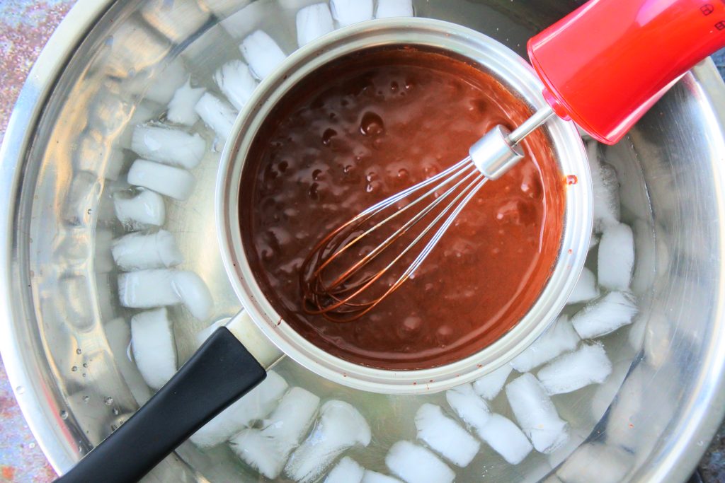 An overhead image showing a small sauce pan of chocolate mixture being whipped into a chocolate mousse while sitting in an ice bath