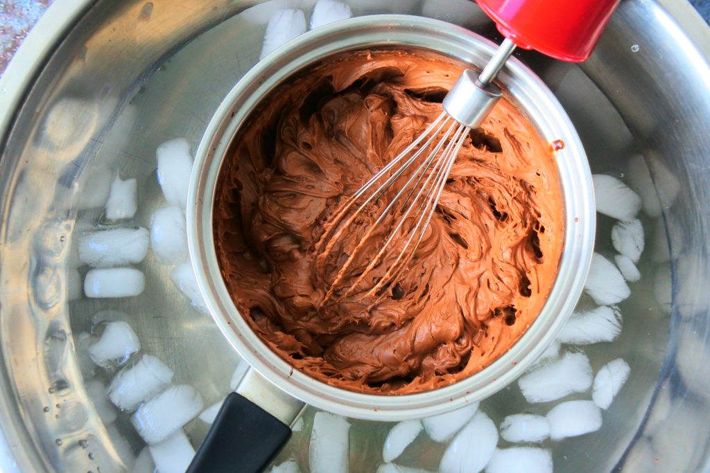 An overhead image showing a small sauce pan of chocolate mixture being whipped into a chocolate mousse while sitting in an ice bath