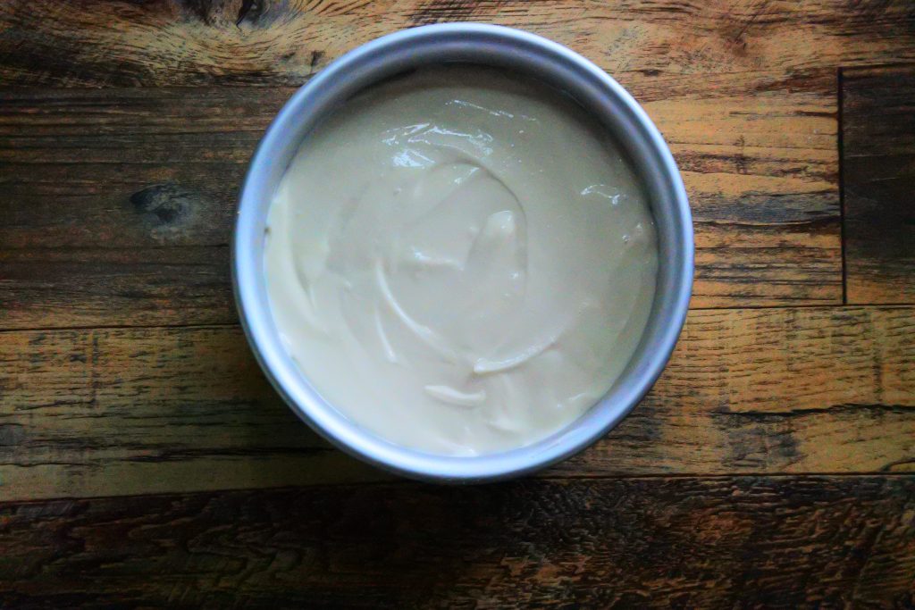 An overhead image showing the filling after being poured and spread evenly over the crust for a gluten-free Greek Yogurt Cheesecake