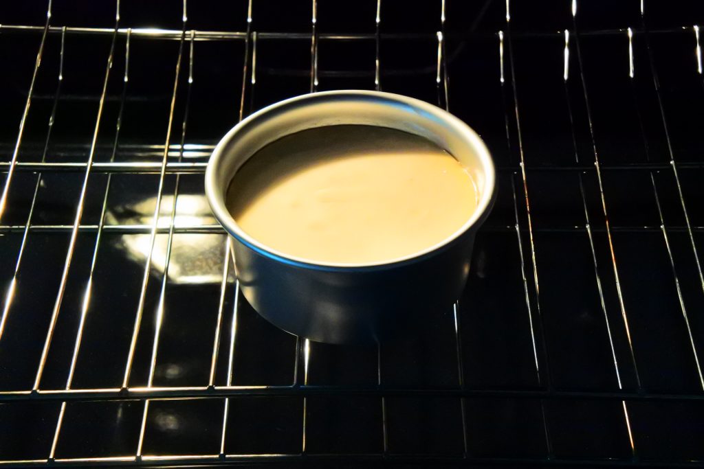 An angled image showing a how the edges of a gluten-free Greek yogurt cheesecake should look after being baked with the edge ring slightly browned and pulling away from the side