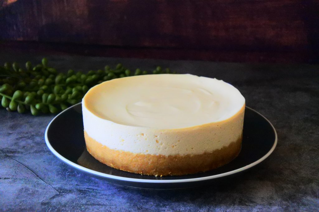 An angled image of a gluten-free Greek yogurt cheesecake on a black plate