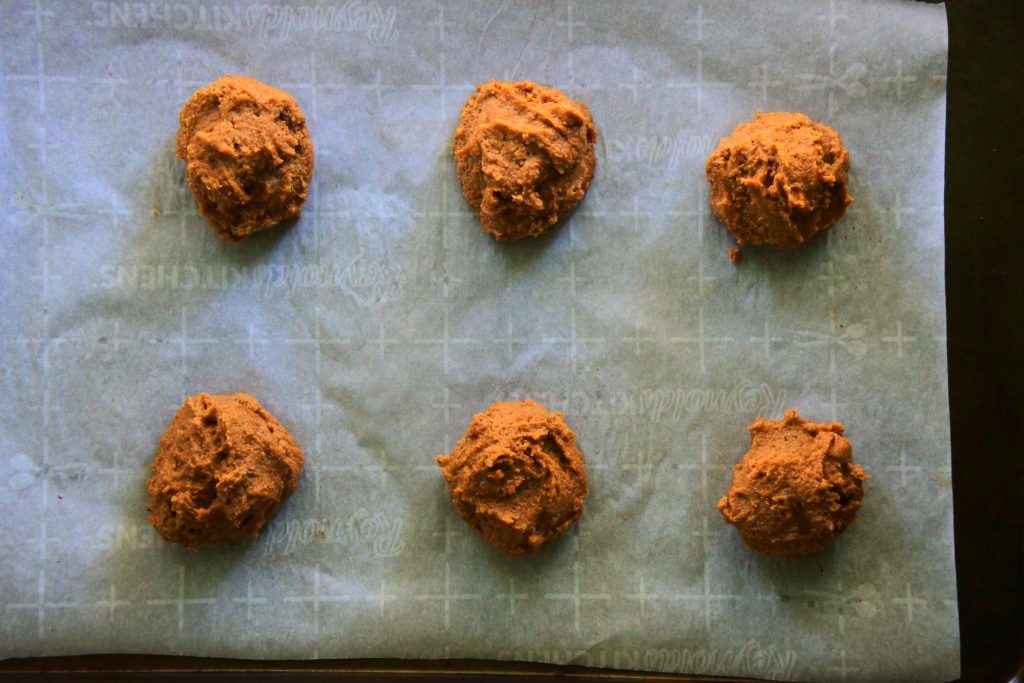 An overhead image of scoops of gluten free gingerbread cookie dough on a tray before being baked