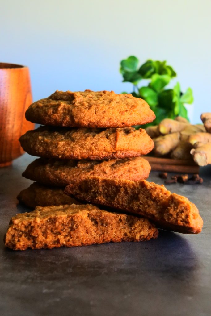 A head on image of a stack of golden big and soft gingerbread cookies with one being split in half
