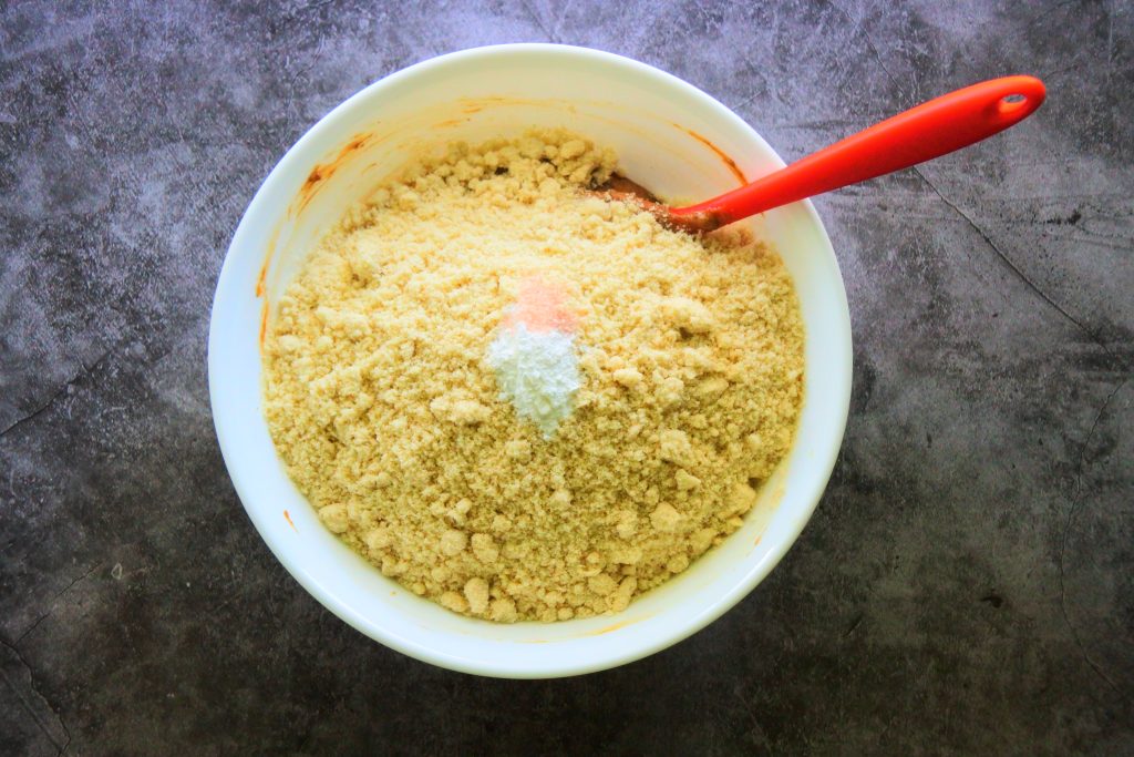 An overhead image of a bowl of gluten free gingerbread cookie dough being made as the dry ingredients are being added in