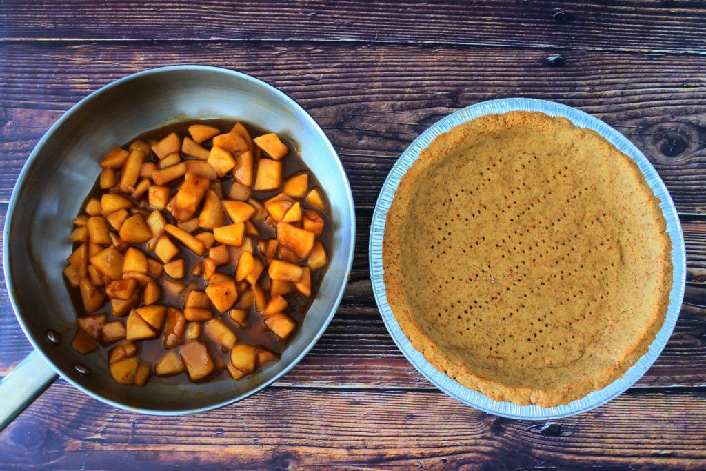 An overhead image of a prebaked pie crust next to a pan of apple pie filling
