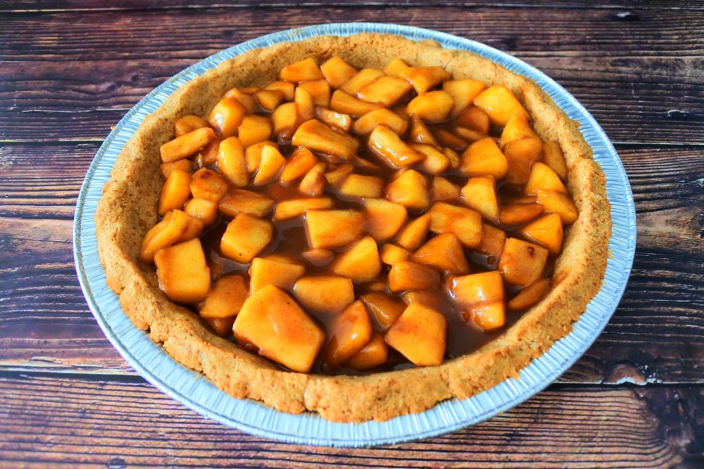 An overhead image of a homemade pie crust filled with a homemade apple filling