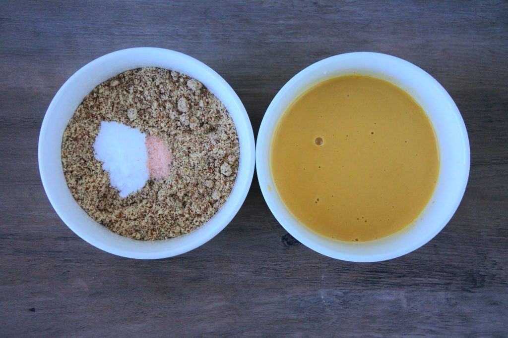An overhead image of two bowls. The left containing almond flour, salt, and baking soda, and the right containing egg yolks, coconut sugar, coconut milk, and vanilla.