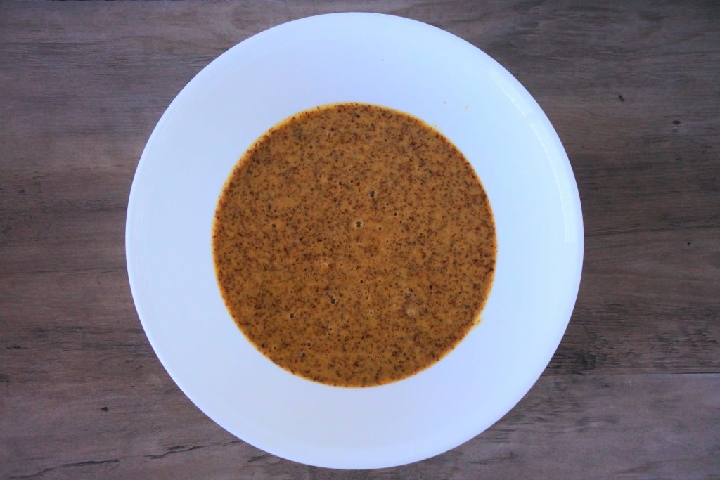 An overhead image of a bowl containing a mixture of almond flour, salt, and baking soda, egg yolks, coconut sugar, coconut milk, and vanilla