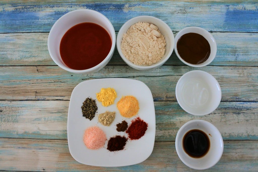 An overhead image of ingredients for a homemade bbq sauce including tomato sauce, sugar, molasses, vinegar, worcestershire sauce and various spices