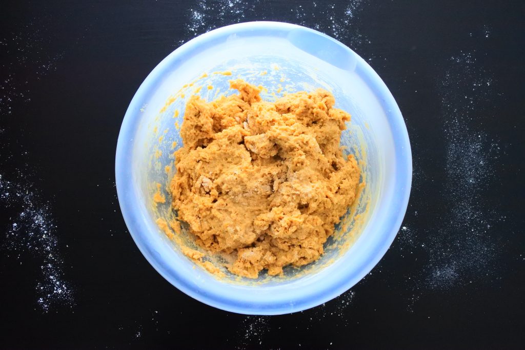 An angled image of bread dough in a bowl on a floured work surface