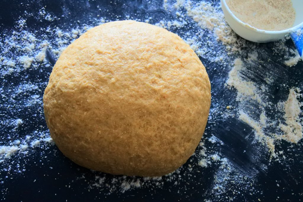 A close up image of a ball of dough on a floured surface