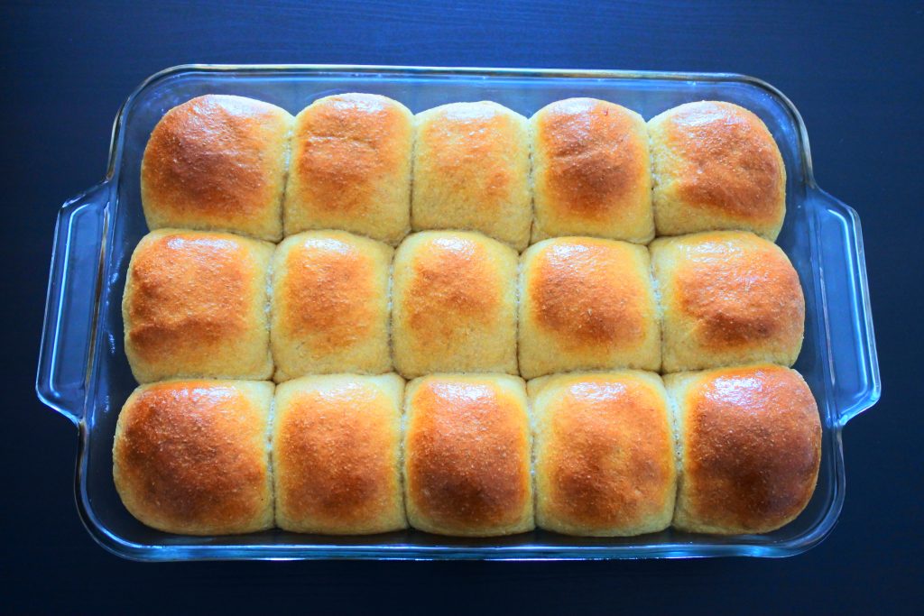 An overhead image of a glass baking dish with fifteen baked Hawaiian dinner rolls