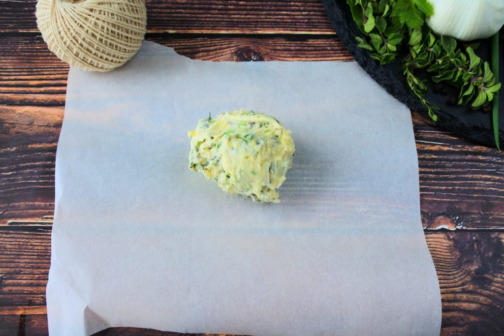 An overhead image of herbed butter on parchment paper