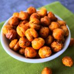 An angled overhead image of a dish of crunchy oven roasted chickpeas on a green linen napkin