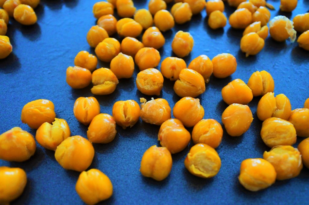 An angled image of partially oven roasted chickpeas on a tray