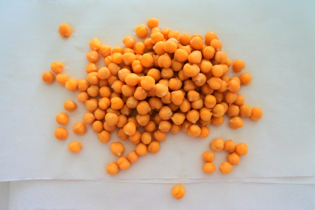 An overhead image of chickpeas being drained and dried on a paper towel