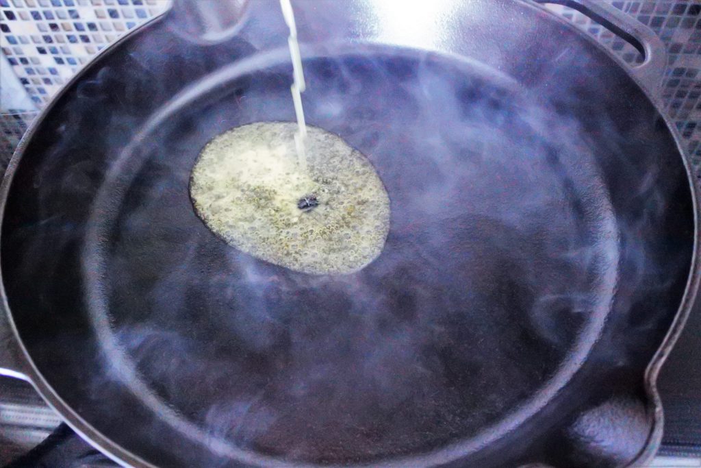 An angled image of melted butter being poured into a hot cast iron skillet