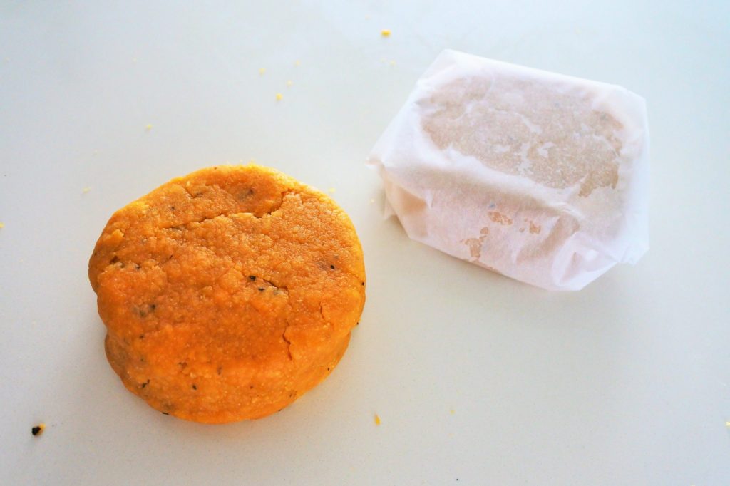An overhead image of chickpea cracker dough formed into a disc with another one wrapped in parchment paper