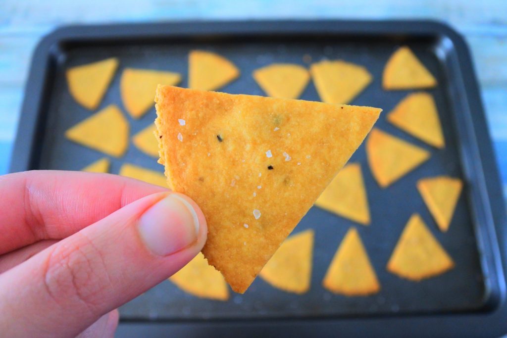 A close up image of a cheesy chickpea cracker being held