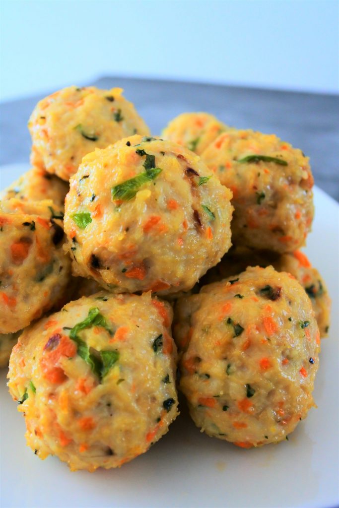 A head on close up image of a pile of baked thai chicken meatballs on a plate.