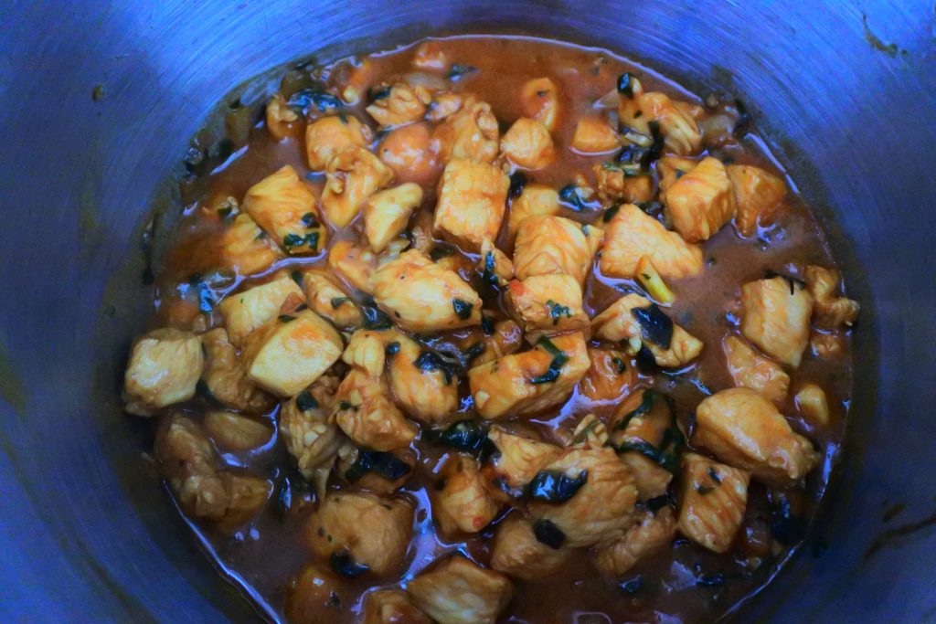 An overhead image of a pot of chicken cubes stewing