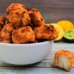 A close up image of a bowl of popcorn chicken with some lemons and limes in the background