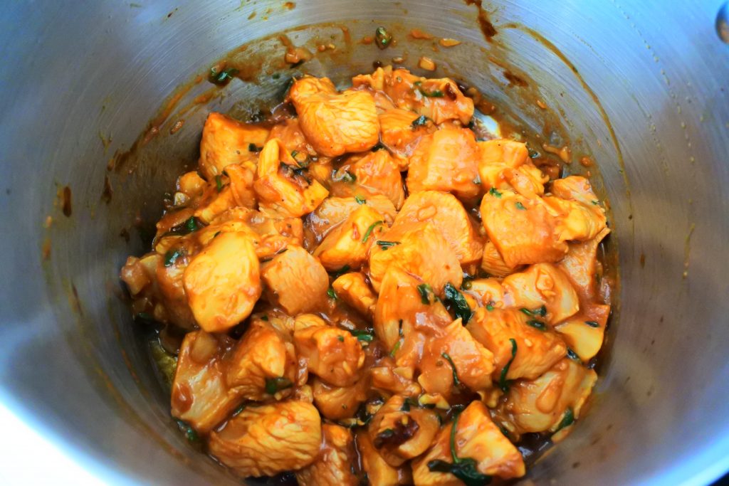 An angled image of seasoned chicken tossed in caramelized raw organic sugar