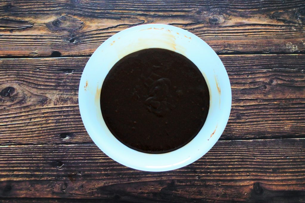 An overhead image of a bowl of brownie batter on a wooden work surface