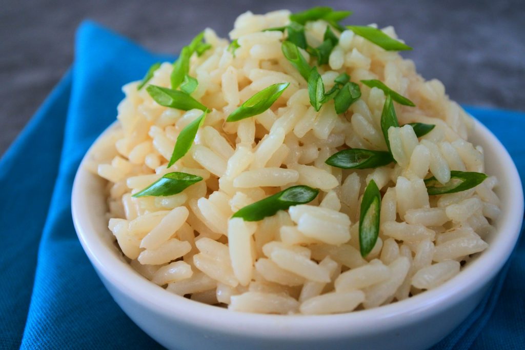 A head on image of a bowl of coconut infused rice topped with sliced chives