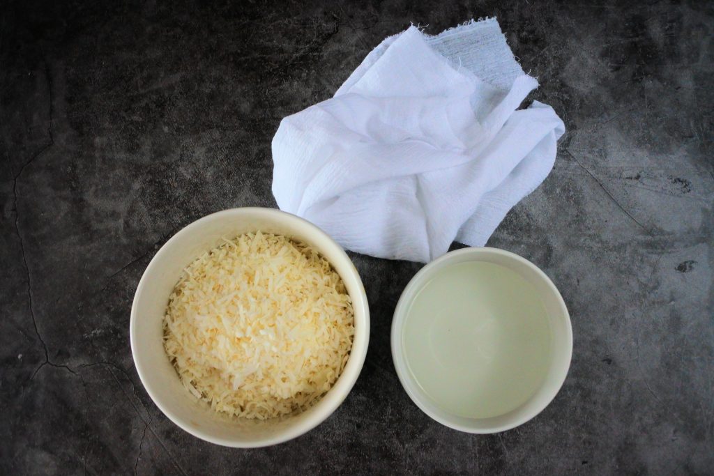 An overhead image of shredded coconut, water and a cheese cloth