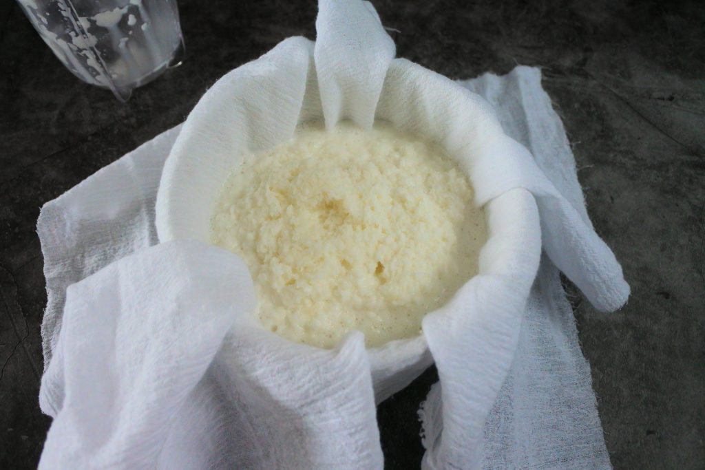 An overhead image of a bowl of coconut pulp in a cheese cloth