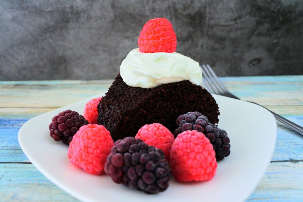 A head on image of a slice of chocolate cake with berries and coconut whipped cream
