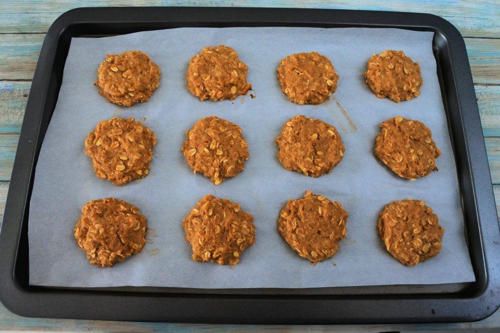 An angled image of a parchment-lined baking tray with baked banana oatmeal cookies on it