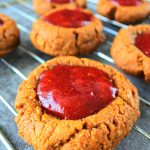 A close up image of a PB&J thumbprint cookies on a wire cooling rack
