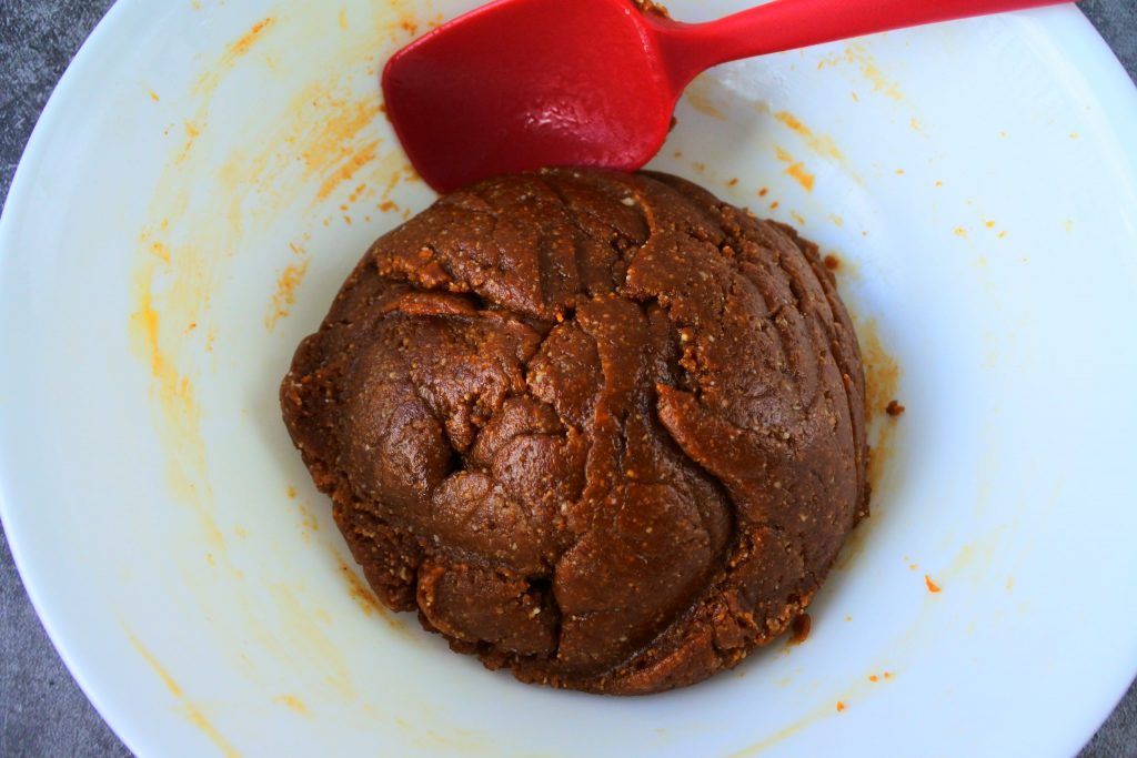 An overhead image of a bowl with peanut butter cookie dough in it along with a red silicone spatula