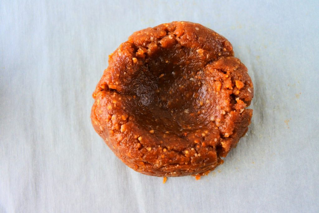 An overhead close up image of peanut butter cookie dough ball with an indent made in the middle