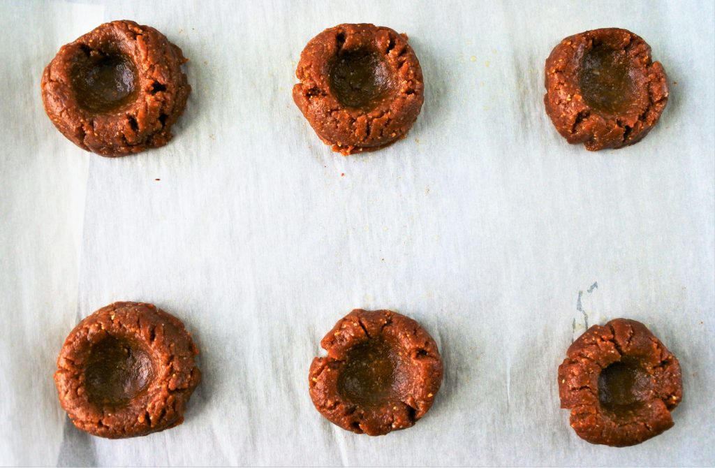 An overhead image of peanut butter cookie dough balls with indents made in the middle