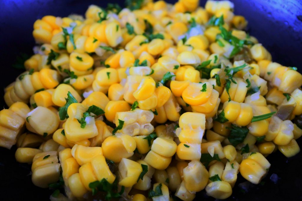 Close up image of corn tossed with spices and herbs for a corn salsa