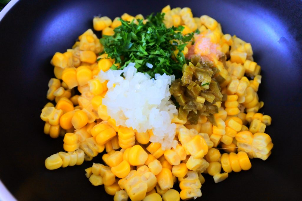 A close up image of fresh corn with add-ins for a corn salsa added in