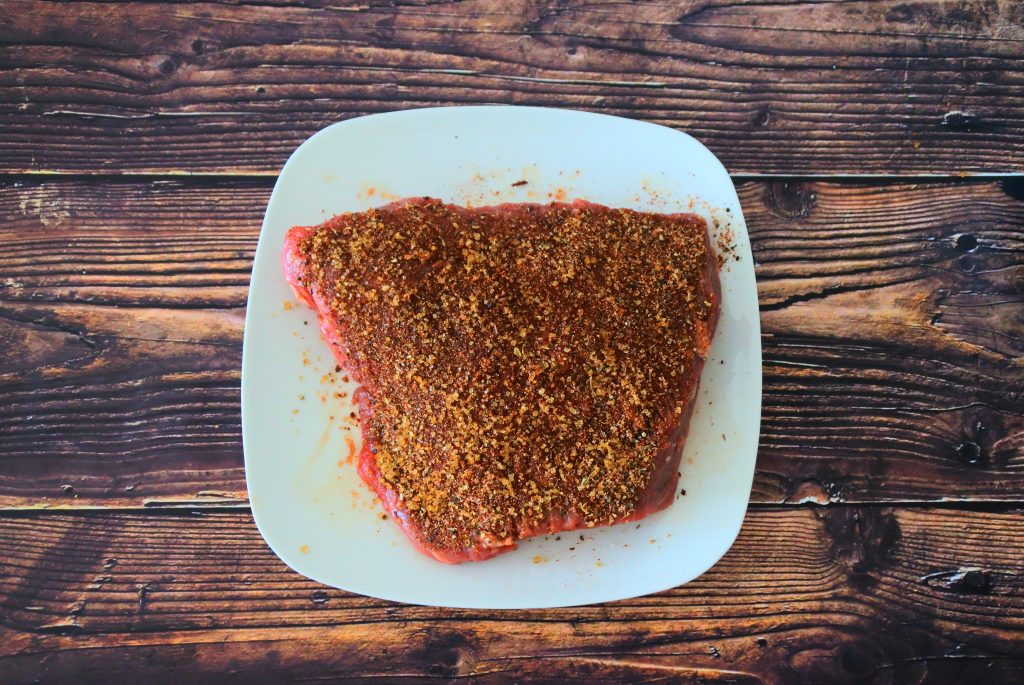 An over head image of a slab of steak with a spice and sugar rub on it